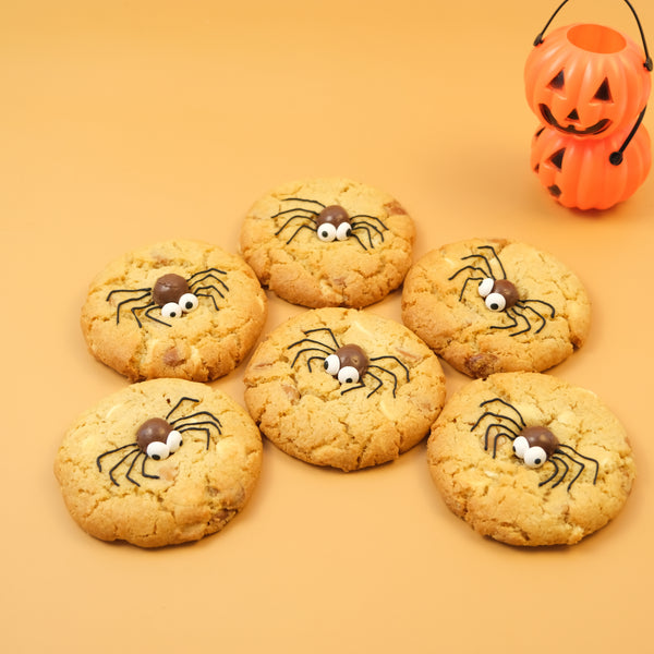 Spooky Spider NY Style Halloween cookies topped with edible chocolate spiders and googly eyes beside a pumpkin decoration
